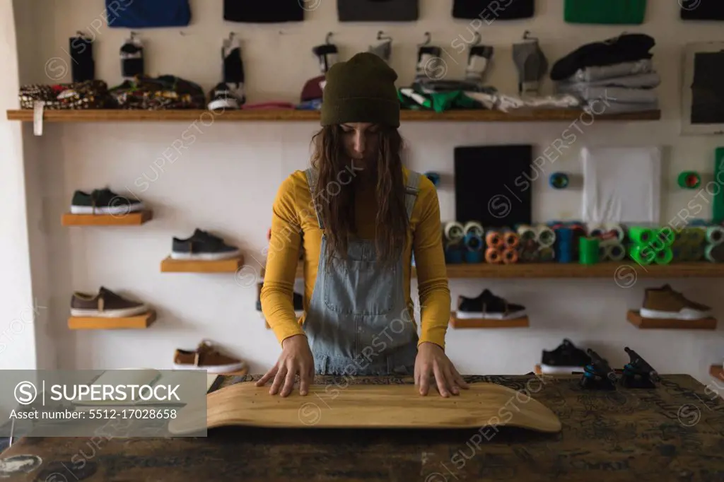 Young woman examining skateboard deck in workshop