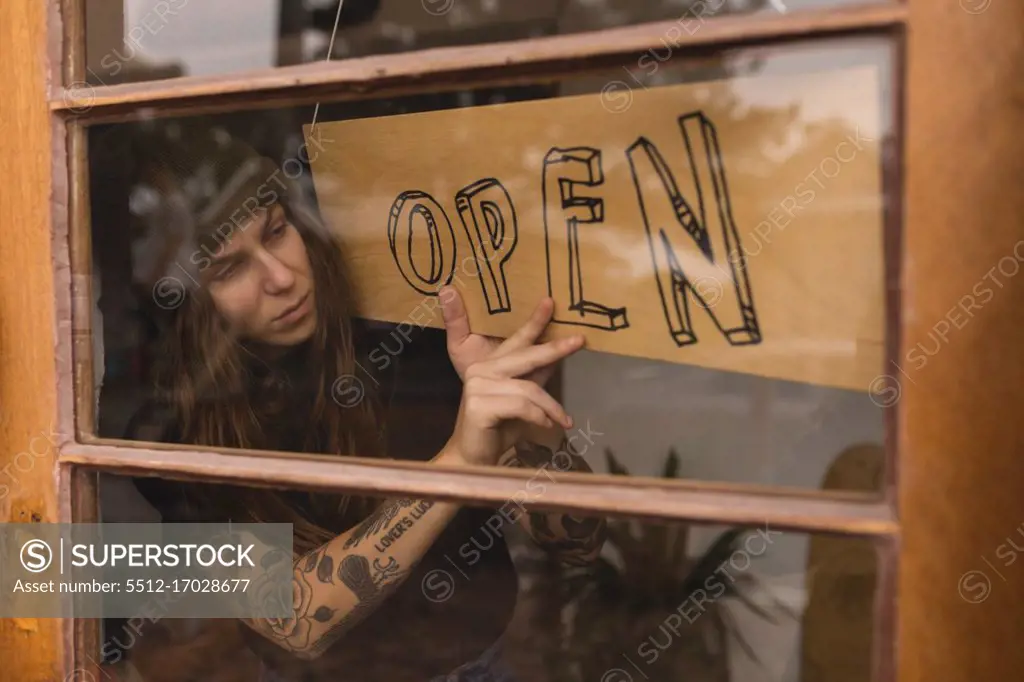 Young woman flipping open signboard in workshop