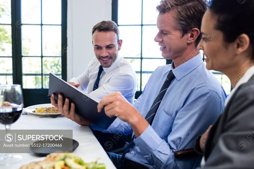 Business colleagues looking at a file and discussing in restaurant