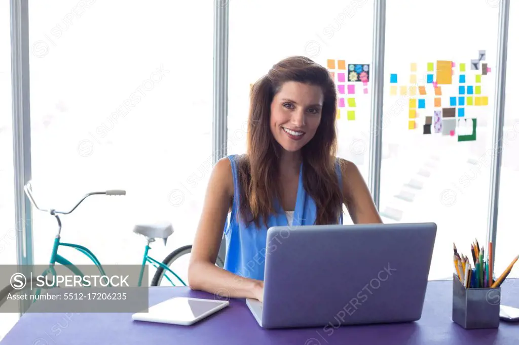 Portrait of female executive using laptop in office