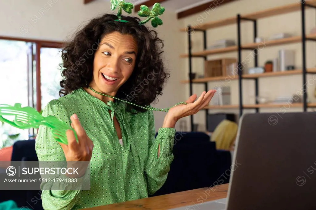 Caucasian woman dressed in green with shamrock deely boppers for st patrick's day talking during video call. staying at home in self isolation during quarantine lockdown.