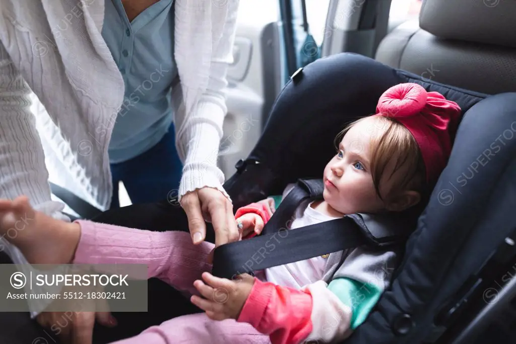 Mid section of mother putting her baby in safety baby seat in the car. motherhood, love and baby care concept