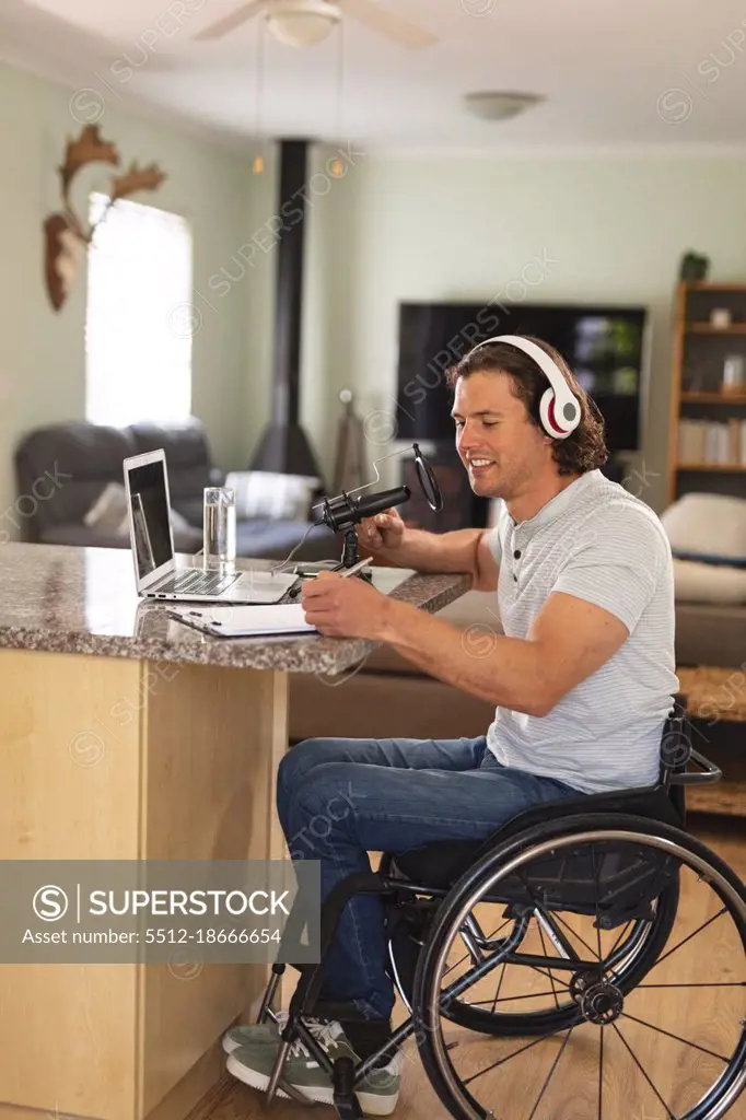 Caucasian disabled man recording podcast using microphone sitting at home. blogging, podcast and broadcasting technology concept