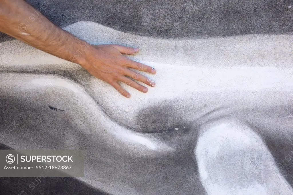 Cropped hand of male artist touching beautiful whale mural painting on wall. street art and skill.
