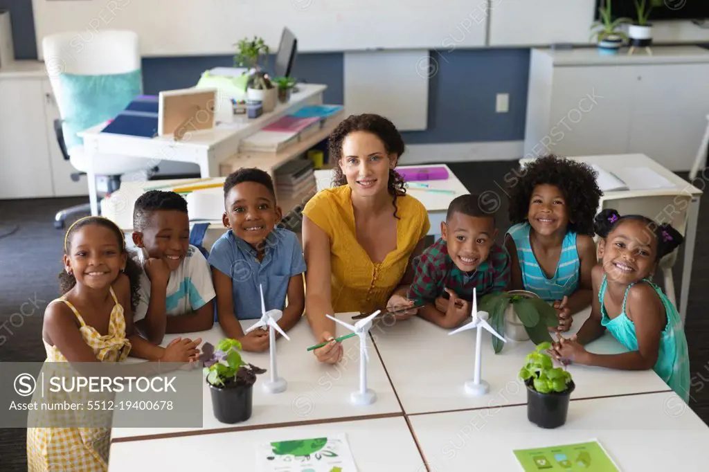 Portrait of african american students with caucasian young female teacher with windmill models. unaltered, education, environment, teaching, sustainable lifestyle and school concept.