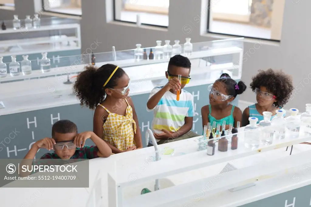 African american elementary school students performing chemical experiment in laboratory. unaltered, education, learning, laboratory, stem, experiment, protection and school concept.