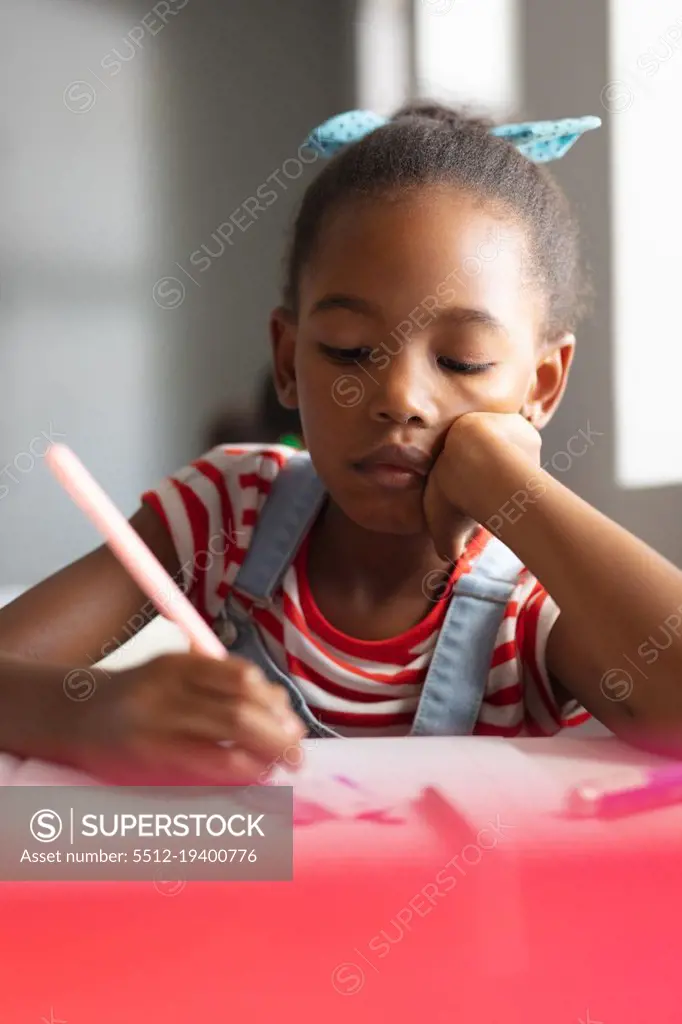 Close-up of african american elementary schoolgirl drawing on book at desk in classroom. unaltered, education, learning, art, childhood, studying and school concept.