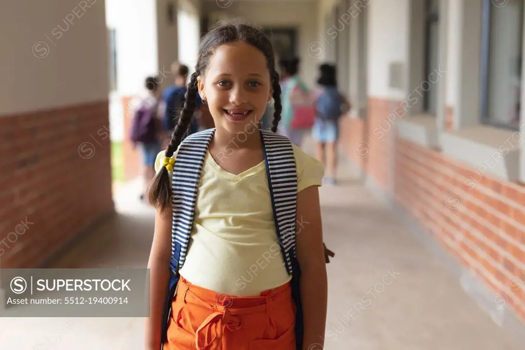 Portrait of happy caucasian elementary schoolgirl standing in corridor. unaltered, education, childhood and school concept.