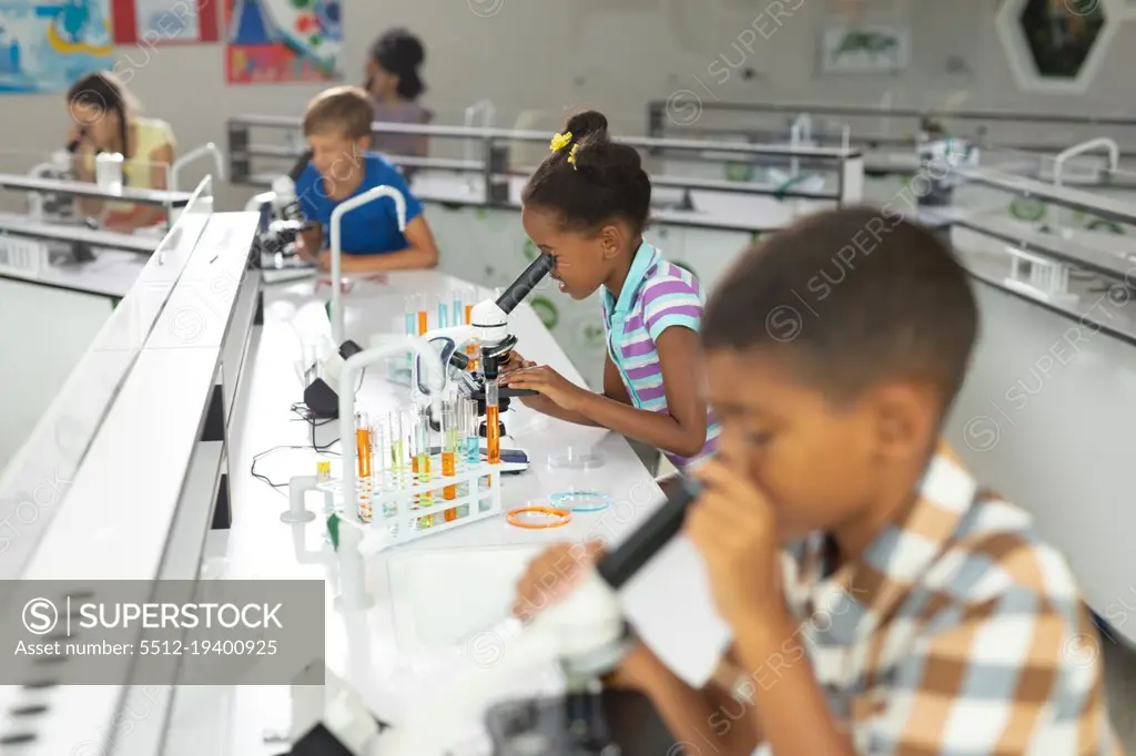 Multiracial elementary students using microscope during science practical in laboratory. unaltered, education, childhood, learning, science, stem, chemical and school concept.