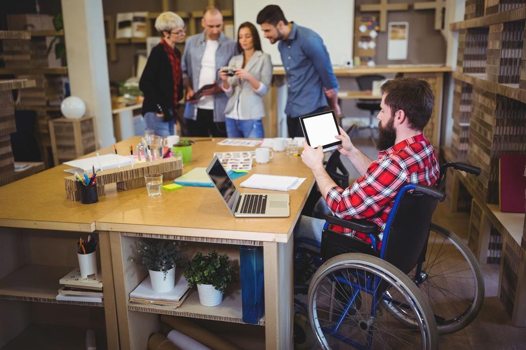 Disabled businessman using digital tablet at desk in creative office