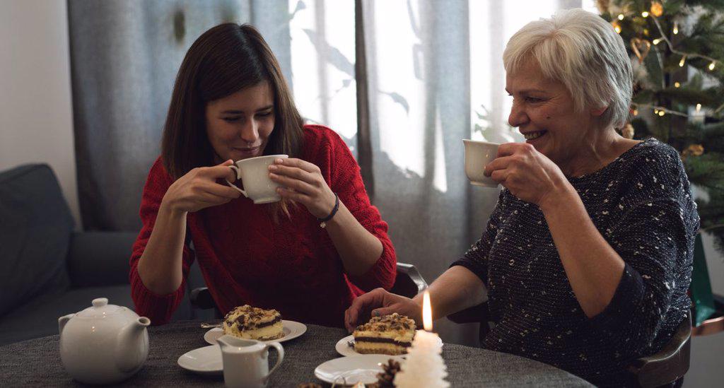Happy mother and daughter having good tea time during Christmas at home