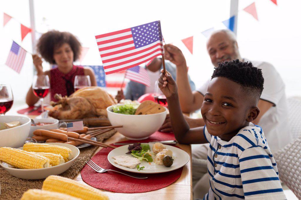 Side view of Multi-generation African American family celebrating US Independence day on a dining table at home
