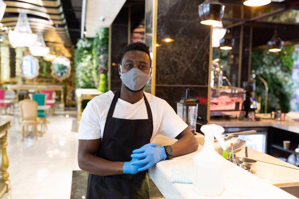 Portrait african american male barista wearing face mask looking at the camera. health and hygiene in business during coronavirus covid 19 pandemic.