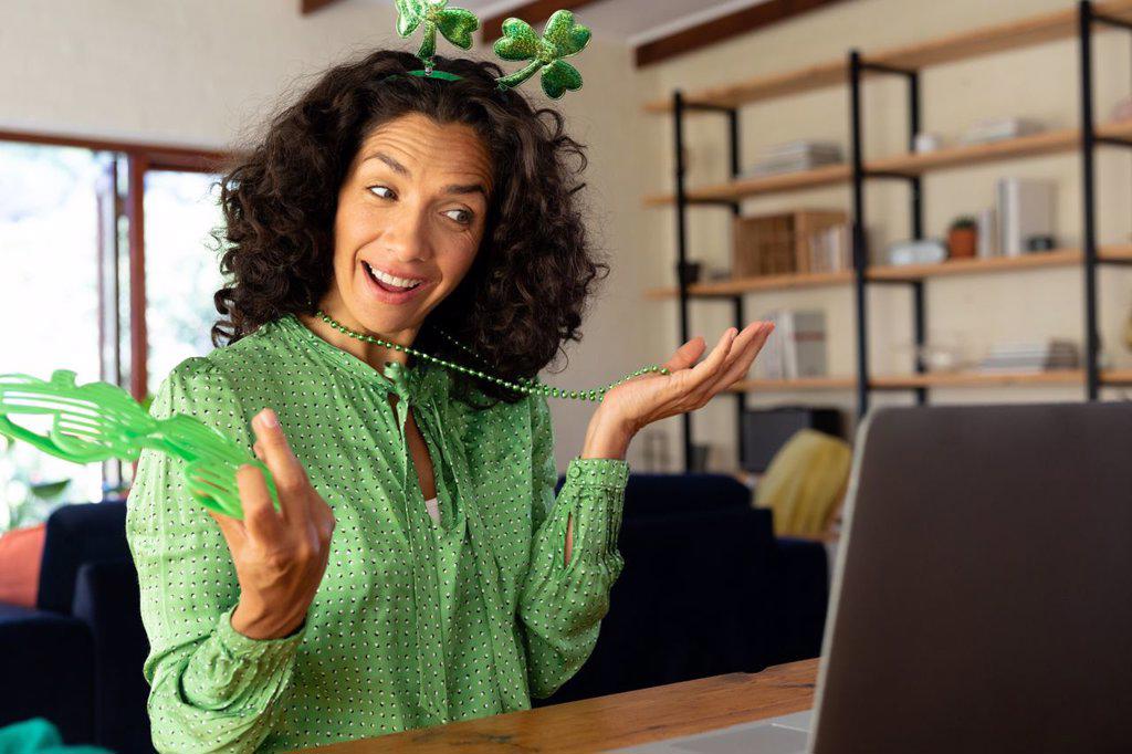 Caucasian woman dressed in green with shamrock deely boppers for st patrick's day talking during video call. staying at home in self isolation during quarantine lockdown.