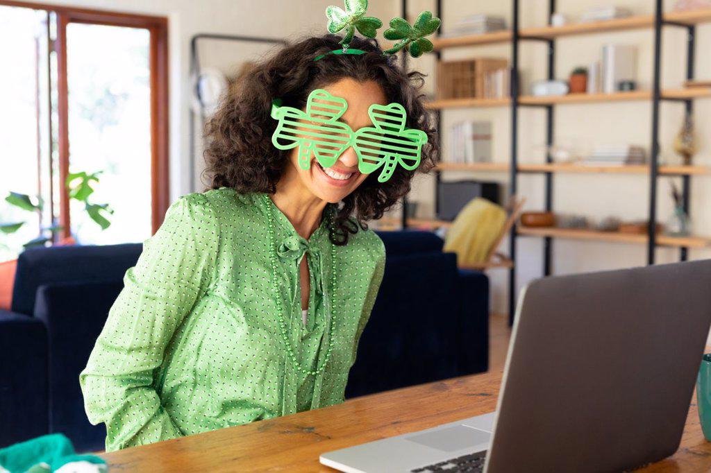 Caucasian woman dressed in green with shamrock glasses making st patrick's day video call. staying at home in self isolation during quarantine lockdown.