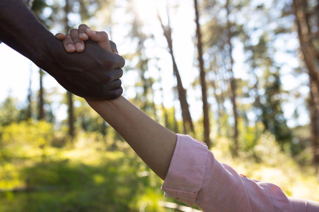 Close up of diverse couple holding hands in countryside. healthy, active outdoor lifestyle and leisure time.