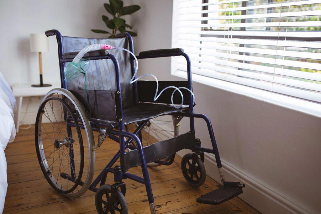 Empty wheelchair with hanging oxygen mask in bedroom at home. healthcare and lifestyle during covid 19 pandemic.