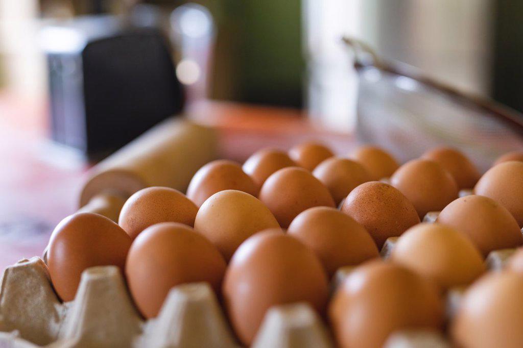 Close-up of fresh brown eggs in carton on table in kitchen at home. organic and healthy eating.