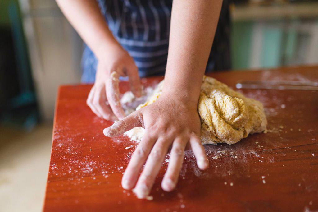 Midsection of woman kneading dough on wooden table in kitchen at home. domestic lifestyle and healthy eating.