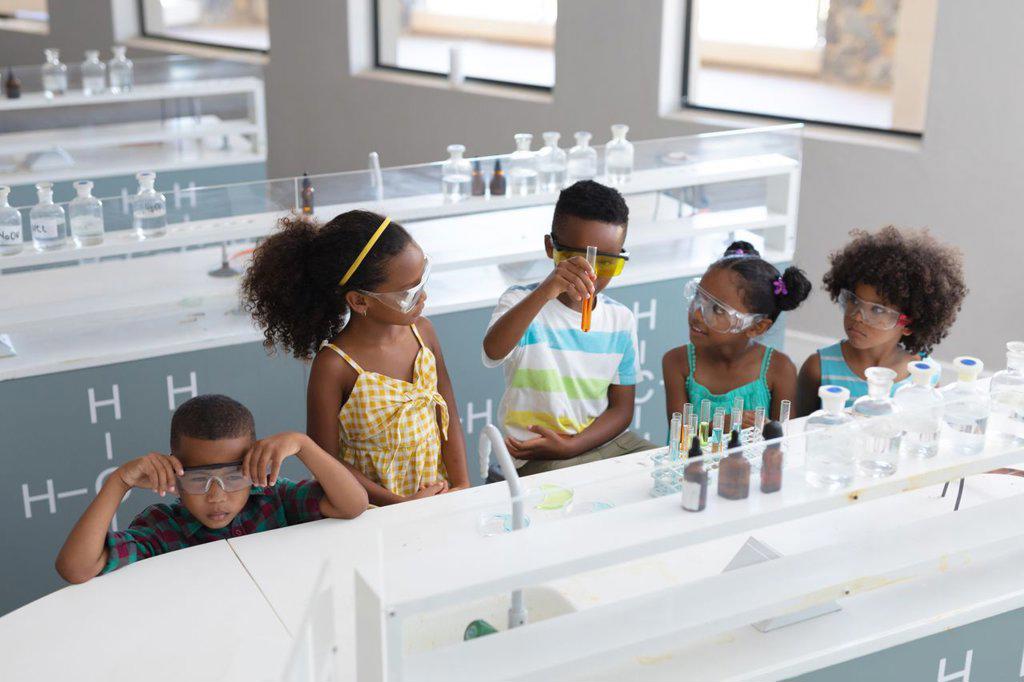 African american elementary school students performing chemical experiment in laboratory. unaltered, education, learning, laboratory, stem, experiment, protection and school concept.