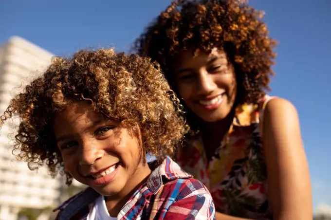 Front view close up of a young mixed race woman and her pre-teen son enjoying time together on a sunny day
