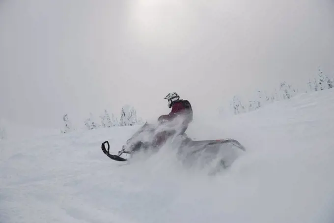 Man riding snowmobile in snowy alps during winter