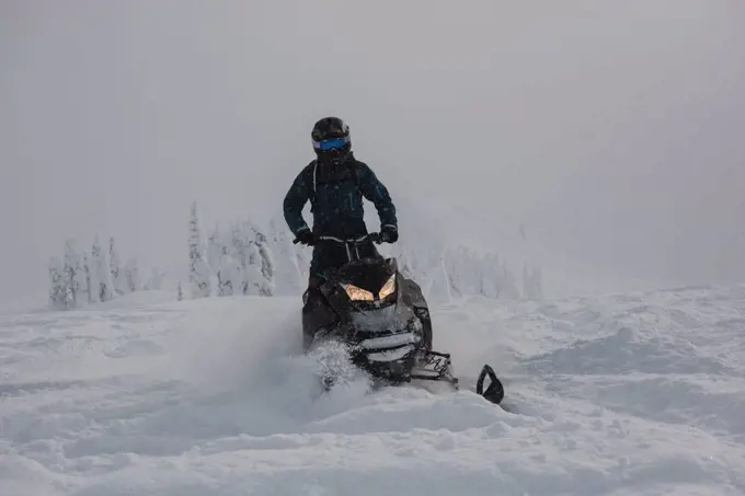Man riding snowmobile in snowy alps during winter