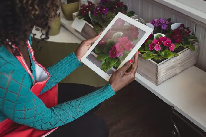 Close-up of female florist taking photograph on digital tablet of flower bouquet