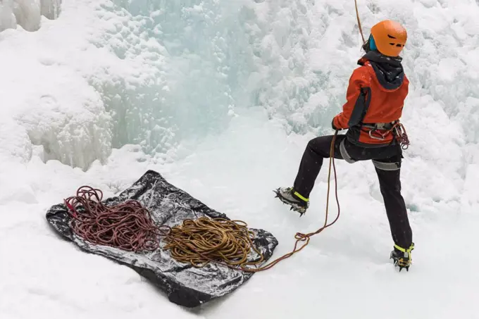 Rear view of female rock climber holding a rope during winter