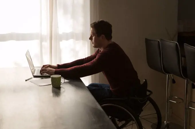 Disabled man using laptop on dinning table at home