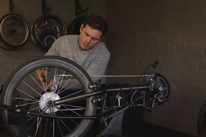 Young disabled man repairing wheelchair at workshop