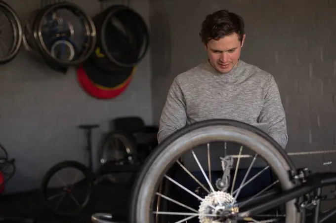 Young disabled man repairing wheelchair at workshop