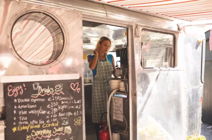 Beautiful female waiter preparing coffee in food truck