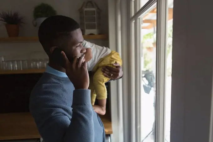 Father with his son in his arms talking on the phone at home