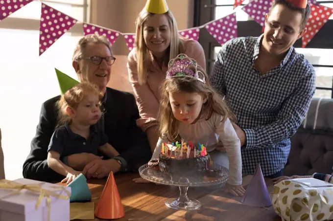 Multi-generation family celebrating birthday in living room at home
