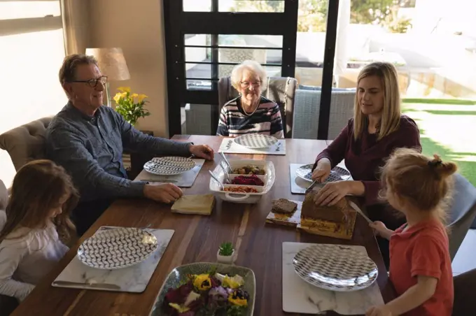 Multi generation family having food on dining table at home