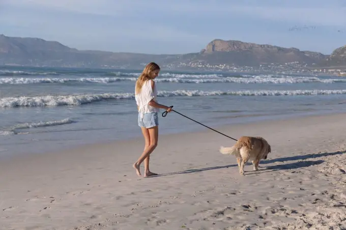 Caucasian woman walking a dog at the beach. healthy outdoor leisure time by the sea.