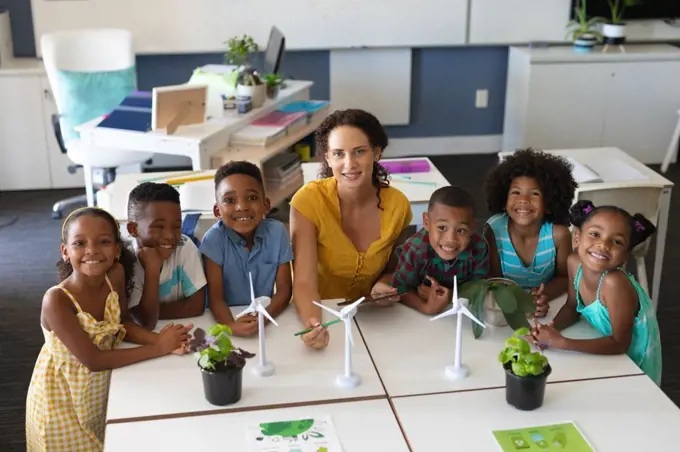 Portrait of african american students with caucasian young female teacher with windmill models. unaltered, education, environment, teaching, sustainable lifestyle and school concept.