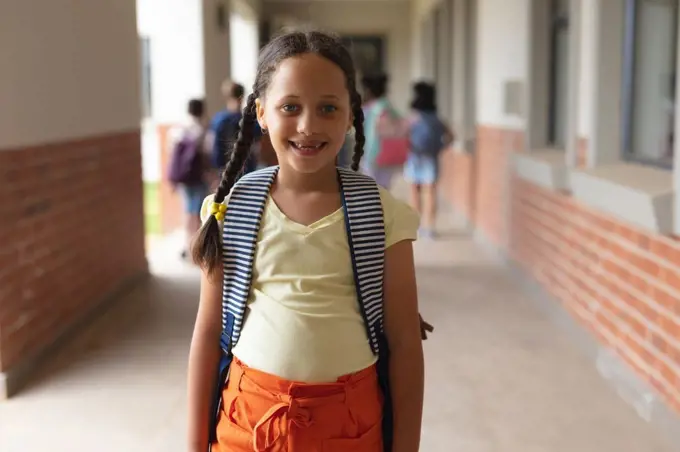 Portrait of happy caucasian elementary schoolgirl standing in corridor. unaltered, education, childhood and school concept.