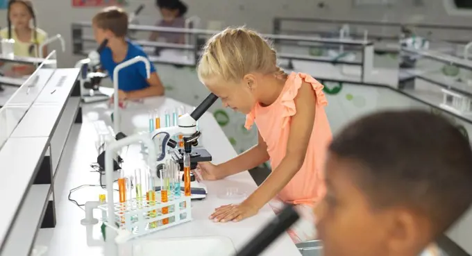 Multiracial elementary students looking through microscope during science class. unaltered, education, childhood, learning, science, stem, chemical and school concept.