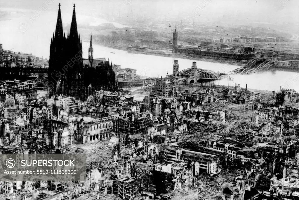 Cologne - Panorama of Destruction: This aerial view of Cologne taken from a Cub spotter plane flying low over the city, gives dramatic illustration of the desolation and devastation wrought on the fourth largest city of the Reich. Cologne Cathedral is seen on the left of the picture structurally undamaged but surrounded by a scene of grim devastation - half submerged in the waters of the Rhine is seen the famous Hohenzollern Bridge blown up by the retreating enemy - who occupy the east side of t
