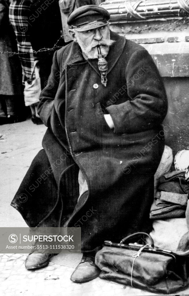 Stock Photo: 5513-111538320 Old German Headed Home: Puffing on his ornate pipe, a Bewhiskered old German sits atop his meager belongings and waits patiently at the an halter station in Berlin for a train which will take him and other German displaced persona out of the German capital. October 22, 1945. (Photo by Associated Press Photo).