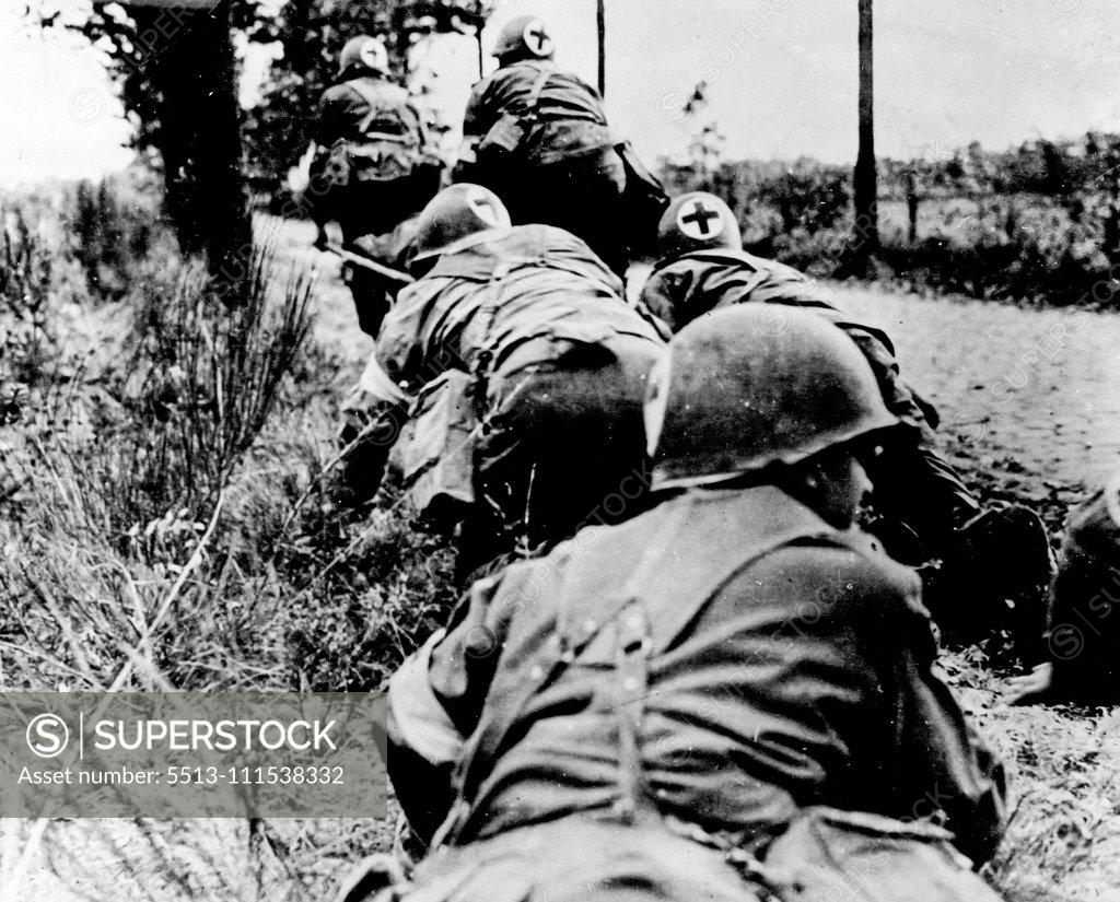 Stock Photo: 5513-111538332 U.S. Army Medical Corps Under Fire: Members of the U.S. Army Medical Corps hurry along a road in Holland which is under fire, carrying an infantryman who was wounded by an 88mm. mortar explosion on a stretcher. In the foreground, the wounded soldier's comrades wait in a ditch for a lull in the fighting before advancing to a new objective. December 4, 1944. (Photo by U.S. Office of War Information Picture).