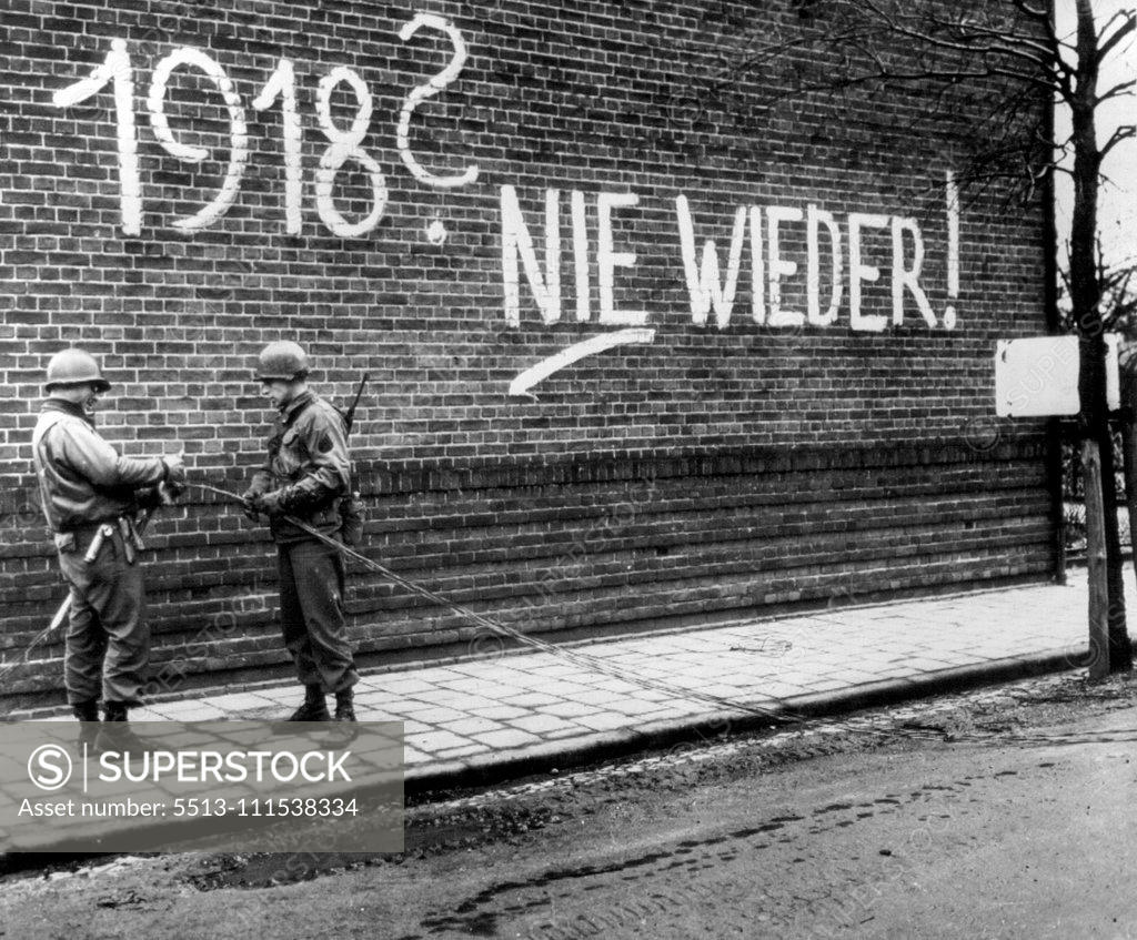 Stock Photo: 5513-111538334 "1918? Never Again" - Two U.S. ninth army signalmen repair wires at a street corner in Echt, Holland, beside a building bearing a painted German propaganda message, reading, "1918? never again!". March 5, 1945. (Photo by AP Wirephoto).
