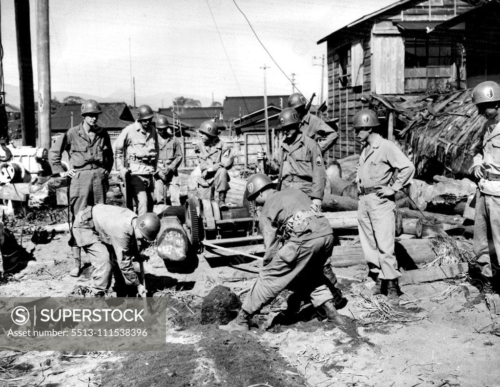 Stock Photo: 5513-111538396 GIs Find Silver Cache in Jap Junk Yard: Yanks of the 132nd Infantry "American" division stand by as two of their buddies uncover a hidden trap door leading to a silver cache in a Japanese junk yard. Discovery of the cache followed a tip as to its whereabouts under a few feet of dirt and discarded machinery. December 3, 1945. (Photo by Associated Press Photo).