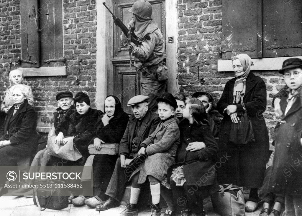 Stock Photo: 5513-111538452 German Civilians Rounded Up By Cologne-Bound 9th: German civilians - young and old - and guarded by an American soldier as they sit outside their homes after being rounded up by the Colognebound U.S. ninth army. Note grey-haired woman sitting at Yank's feet holding a loaf of bread. March 5, 1945. (Photo by Associated Press Photo).