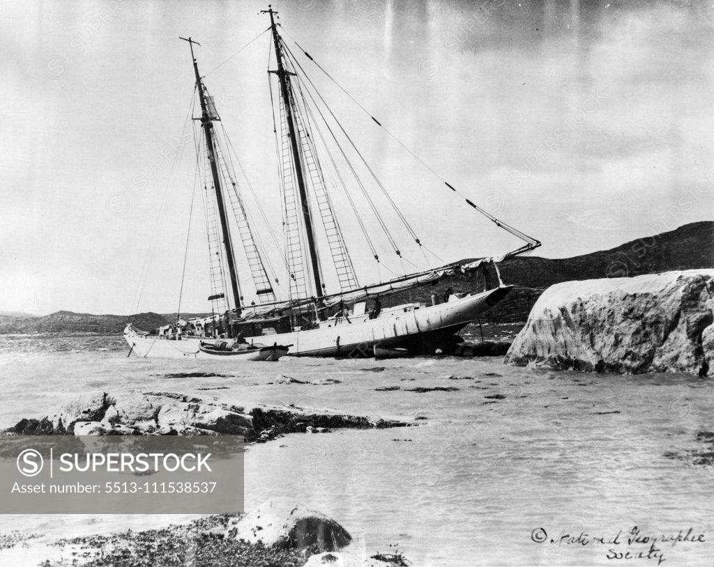Stock Photo: 5513-111538537 With the MacMilland Expedition in the Arctic: The "Bowdoin" the flagship of the MacMillan expedition to the far North, in an improvised dry dock at hopedale. The cargo is piled high on the foredeck, throwing stern in the air, so that a new propellor can be fitted to replace the one broken on the trip up the Labrador coast. Empty casks are also used to raise the propellor shaft above the level of the water. February 16, 1932. (Photo by International Newsreel Photo).