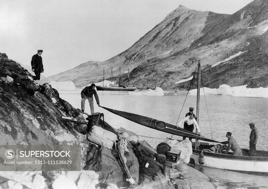 Stock Photo: 5513-111538629 Greenland Air Survey Expedition - Watkins Last Day: Mr. H. G. Watkins, the late leader of the Greenland Artic Air Route Survey Party, who was drowned through a mishap to a kayak (Eskimo Canoe), is shown in our picture helping to unload a kayak at the Base, on the day of the Tragedy. He lost his life while seal hunting. November 21, 1932. (Photo by British Arctic Air Route Expedition Photograph).