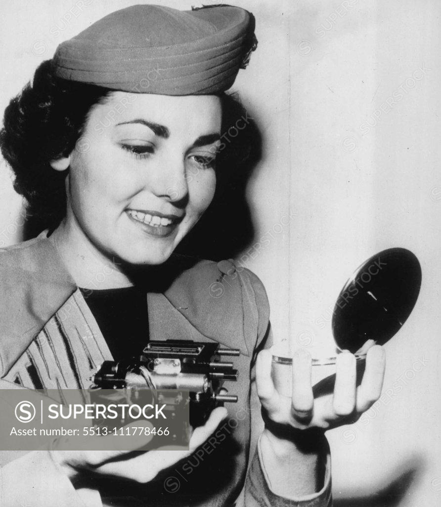 Stock Photo: 5513-111778466 Tiny Motor Helps Fliers -- Jean Jettie, an airline hostess, compares a compact with a tiny hydraulic motor weighing less than a pound and developing 2½ horsepower during a demonstration here of robot gadgets designed to help pilots fly supersonic aircraft. The motor helps operate ailerons, rudders or elevators which otherwise could not be moved because of terrific wind pressures. It was perfected by the Minneapolis-Honeywell Regulator Co., and shown to the Airport Operators' Council convention h