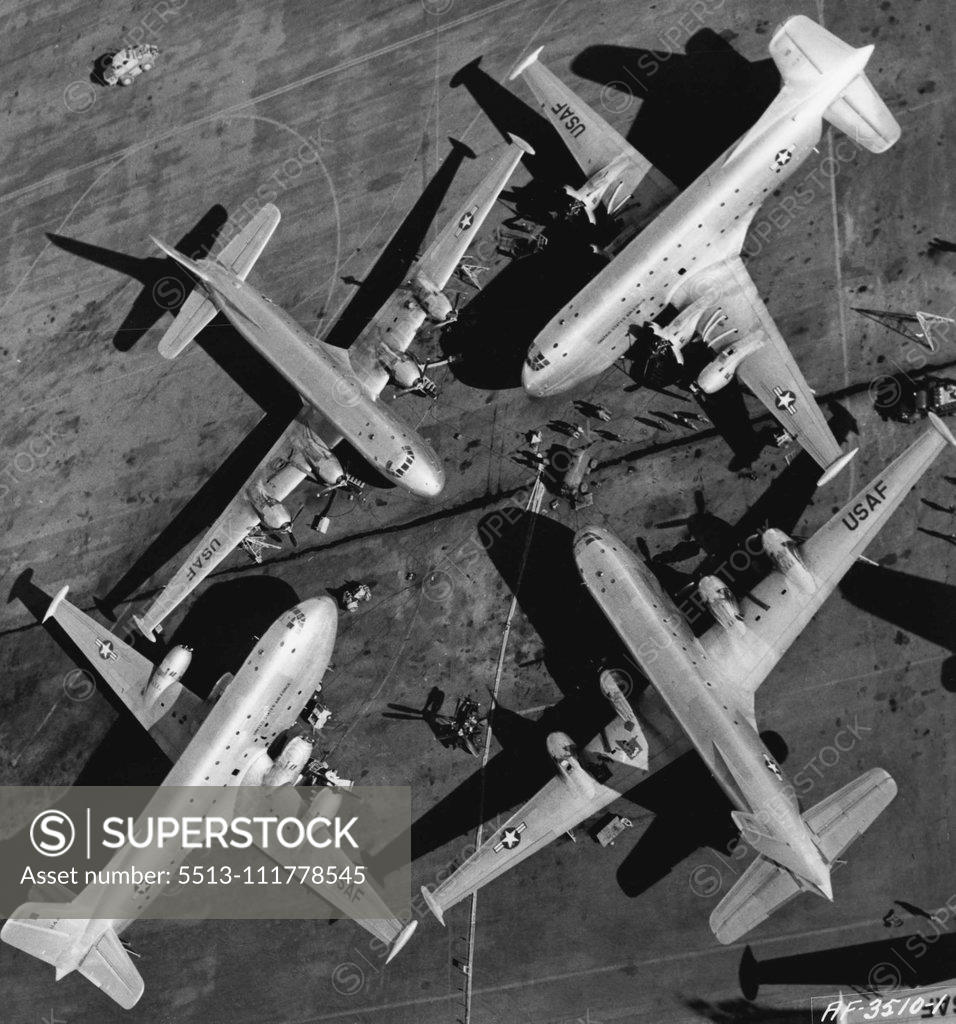 Stock Photo: 5513-111778545 A Quartet Of Winged Giants Four huge U. S. Air Force 0124 Globemasters of the 374th Troop Carrier Wing (Combat Cargo) huddle on the flight line, between Combat Cargo missions on the Korean airlift. This unusual photograph of these three-story mammoths of the air was taken from a helicopter at the 374th base in Japan, while the C-124s of the 315th Air Division were receiving routine maintenance. They were parked this way to make maximum use of a central pool of tools and equipment. The four gia